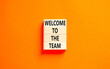 © Dzmitry - Welcome to the team symbol. Concept words Welcome to the team on beautiful wooden block. Beautiful orange table orange background. Business, motivational and welcome to the team concept.