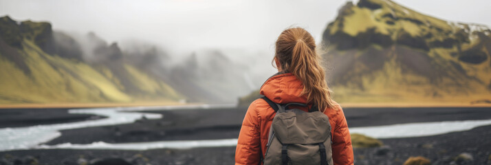 Wall Mural - Young female hiker with a backpack admiring scenic view of spectacular Icelandic nature on a sunset. Breathtaking landscape of Iceland. Hiking by foot.