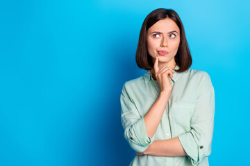 Poster - Portrait of suspicious girl with stylish hairdo wear turquoise blouse thoughtfully look empty space isolated on blue color background