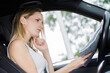confused woman in drivers seat of car looking at map