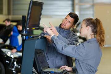 man mechanic and woman looking at pc screen