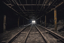 Exploring An Old Abandoned Coal Or Mineral Mine. Dark And Dim Shaft. Old Trolley Tracks