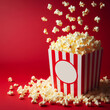 Delicious popcorn scattering from a red striped carton box on red background with copy space