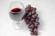© EstúdiosFreeDomArtes - Bunch of grapes with glass of wine on white table. View from above. Clean space for text.