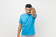 © khosrork - Portrait of unshaven man wearing blue T- shirt standing making stop gesture with his hand, looking at camera with serious strict expression. Indoor studio shot isolated on gray background.