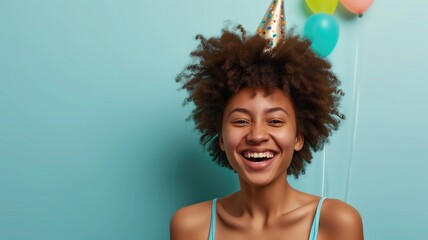 Wall Mural - Young, cheerful woman with a party hat, laughing against a balloon backdrop