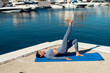 © sutulastock - a sporty girl in sportswear is warming up on the pier against the backdrop of the sea, doing an exercise, stretching. fitness instructor shows exercise. motivation for sports and a healthy lifestyle