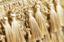 Curtain Tassel Background. Golden Tassel Fabric. Decorative Knot. Elegant Shiny Cord. Silk Chain With Tassels. Textile Texture. Ornamental Eastern Culture Element.