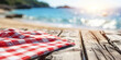 © Gabriela - White and red checkered napkin on rustic wooden table with morning beach background, space for brand or product advertising