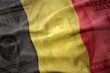 waving colorful flag of belgium on a american dollar money background. finance concept.