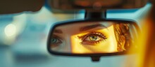 Woman's reflection in a car's rear view mirror