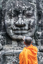 Buddhist Monk Touching Giant Buddha Stone Face Statue, Bayon Temple, Angkor Wat, Cambodia