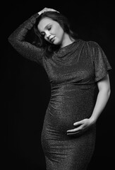 Wall Mural - Black and white portrait of pregnant female in sequin dress with hands near pregnant belly.