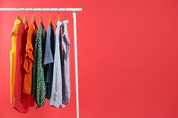 Wall Mural - Bright clothes hanging on rack against red background, space for text. Rainbow colors