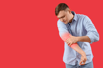 Wall Mural - Young man feeling pain in elbow on red background