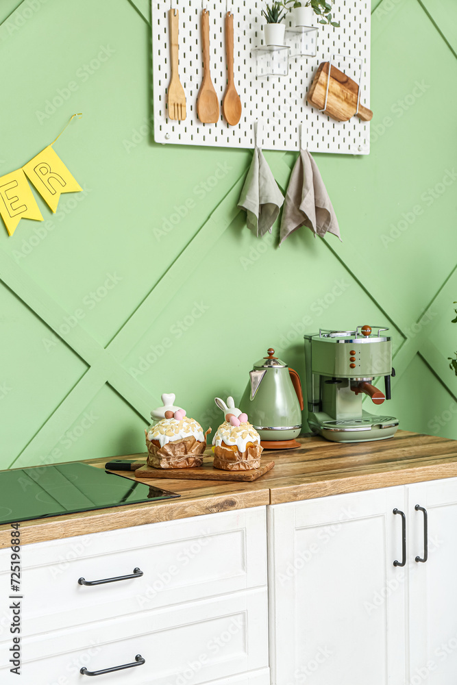 Easter cakes with painted eggs, kettle and coffee machine on white kitchen counter