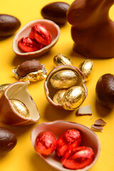 Wall Mural - Chocolate Easter eggs and bunny on yellow background