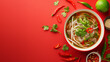 canvas print picture - Top-down view of a vibrant bowl of pho with fresh herbs, chilies, and lime on a red background  with a place for text, suggesting Vietnamese cuisine or culinary concepts