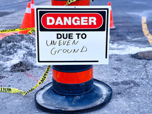 Red Danger Due To Uneven Ground Sign Post On A Construction Site With Yellow Caution Tape Around.