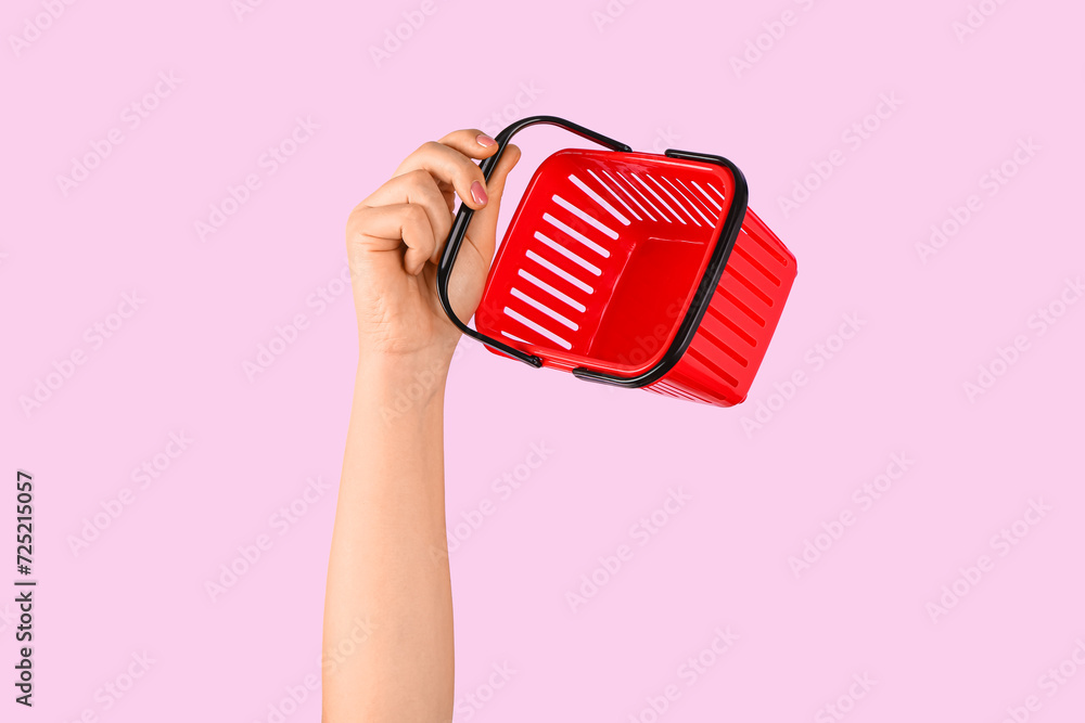 Woman holding mini shopping basket on pink background