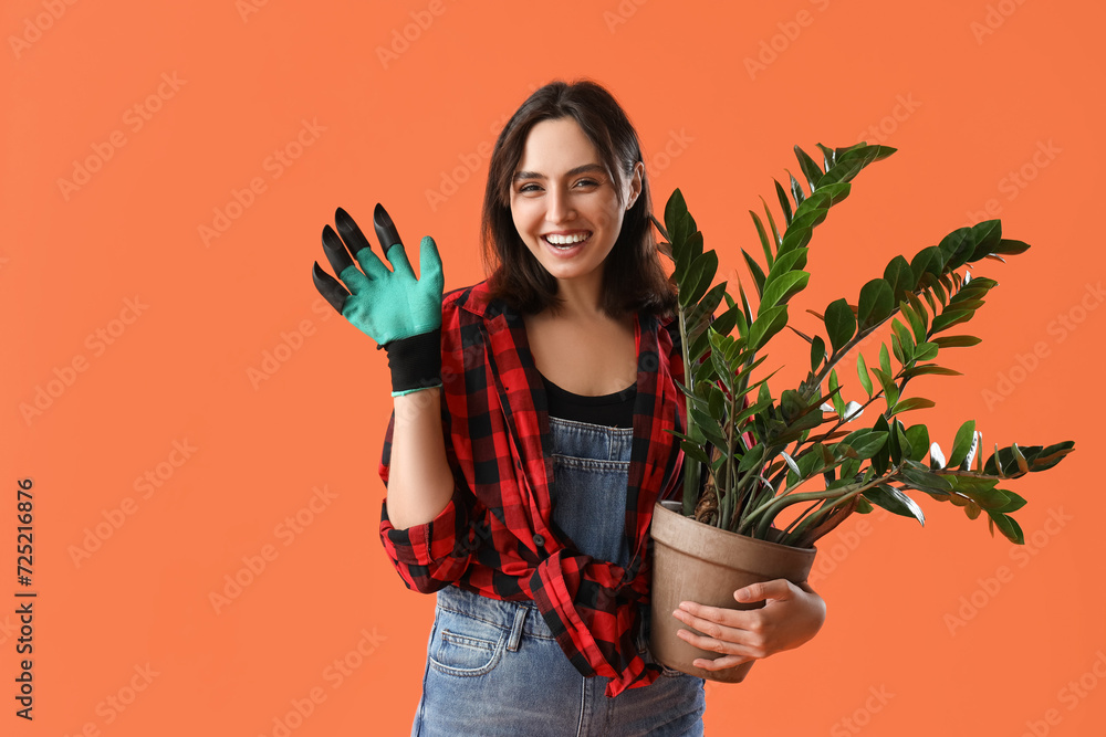 Young woman with plant on orange background