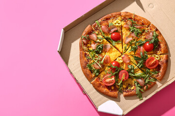 Wall Mural - Cardboard box of delicious pizza with tomatoes and arugula on pink background