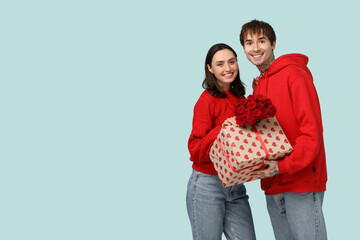 Canvas Print - Young couple with bouquet of roses and gift for Valentine's day on blue background