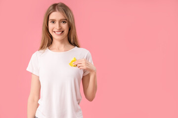 Sticker - Young woman with yellow awareness ribbon on pink background. World Cancer Day