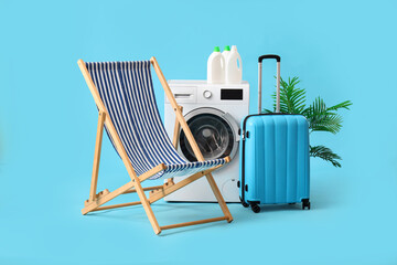 Wall Mural - Washing machine, luggage and deck chair on blue background. Concept of vacation