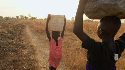 couple of black african child children kids carrying purified water in plastic bucket over their hea