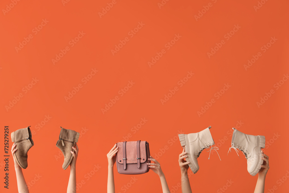 Women with stylish boots and bag on orange background