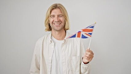 Canvas Print - Blond man smiling, holding union jack flag on white background, conveying happiness and patriotism.