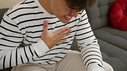 Sticker - Heart-stricken young hispanic man suffers a cardio attack on cozy sofa in sunshine-drenched living room