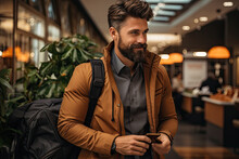 Fashionably Dressed Man With Well-groomed Beard Stands In Modern City Mall, Mobile Phone In Hand, As If Hes Either Just Arrived Or Is Waiting For Someone, Ambient Lighting Creating Inviting Atmosphere