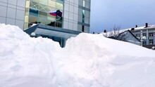Administrative Building With The Flag Of Russia Under Snowdrifts, Snow Debris In Winter. Severe Weather Conditions In The Northern Region In Winter. The Level Of Precipitation In The City. Climate