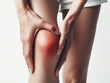 Close-up of a woman's knee holding her knee with her hand due to knee pain
