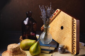 Still life with a bouquet of dried lavender in a transparent vase, dulcimer, books and two pears. Interior paintings, design.