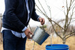 Farmer pouring water with a bucket outdoors on a farm. Water saving, sustainability and environment.