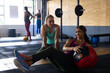 © Wavebreak Media - Diverse young woman motivating friend exercising with fitness ball on floor in health club