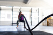 © Wavebreak Media - Dedicated biracial young woman training with battle ropes in health club against window, copy space
