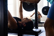 © Wavebreak Media - Midsection of diverse woman assisting friend in lifting barbell while lying on exercise table