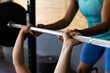 © Wavebreak Media - Cropped hands of diverse woman assisting friend in lifting barbell in health club