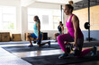 © Wavebreak Media - Diverse young female friends lifting kettlebells while kneeling on floor in health club, copy space