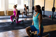 © Wavebreak Media - Diverse female friends lifting kettlebells while kneeling on floor in health club, copy space