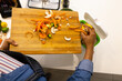 © Wavebreak Media - Overhead view of biracial woman in apron composting vegetable waste in kitchen