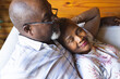 © Wavebreak Media - Happy senior african american couple lying on sofa and embracing at home