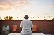 rear view of person on patio gazing at sunset, peaceful posture