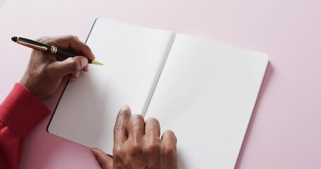 Sticker - Close up of hands holding pen and blank pages of book, copy space on pink background, slow motion