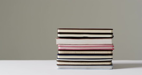 Canvas Print - Close up of stack of books on grey background, in slow motion