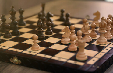 The chess board with the pieces in the dark vintage room interior